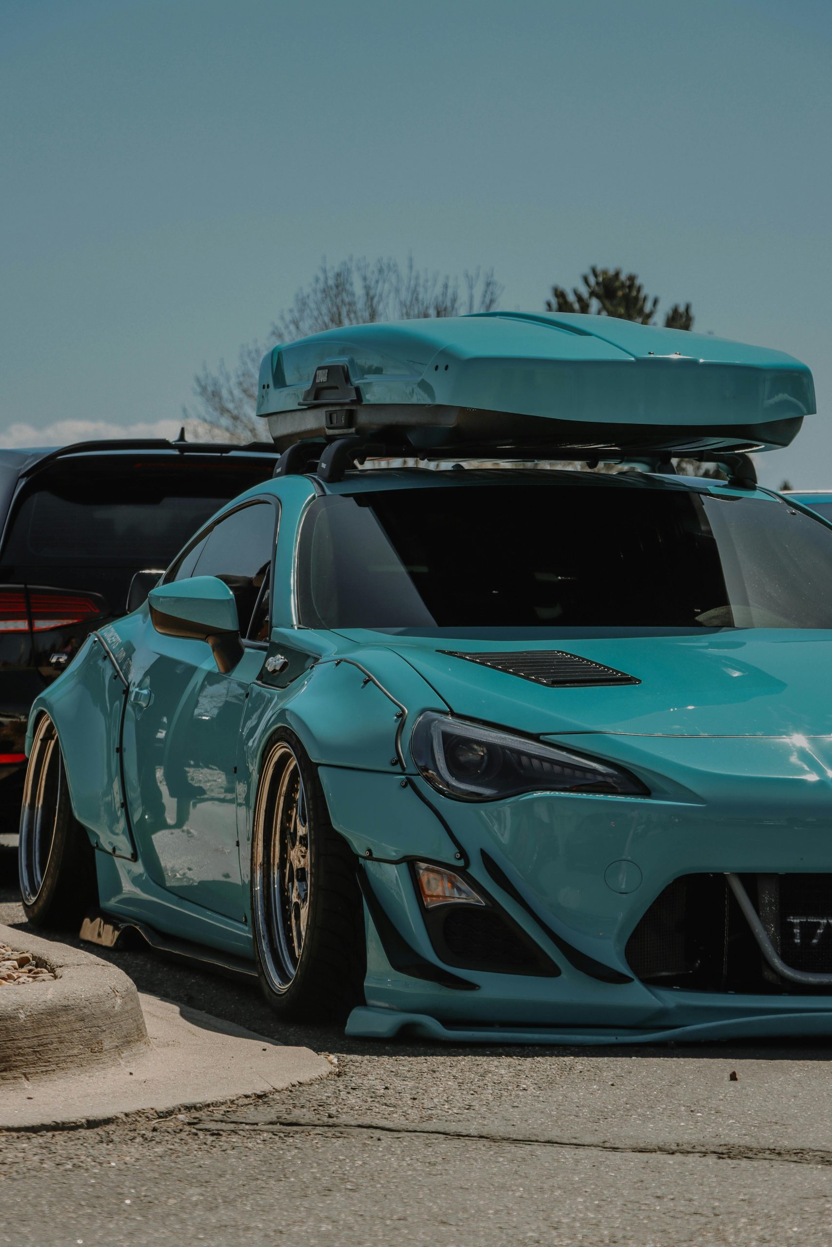 A modded teal sports car parked on a street in Denver, showcasing custom design and vibrant style.