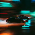 Long exposure shot capturing the vibrant motion blur of cars speeding through a city street at night.